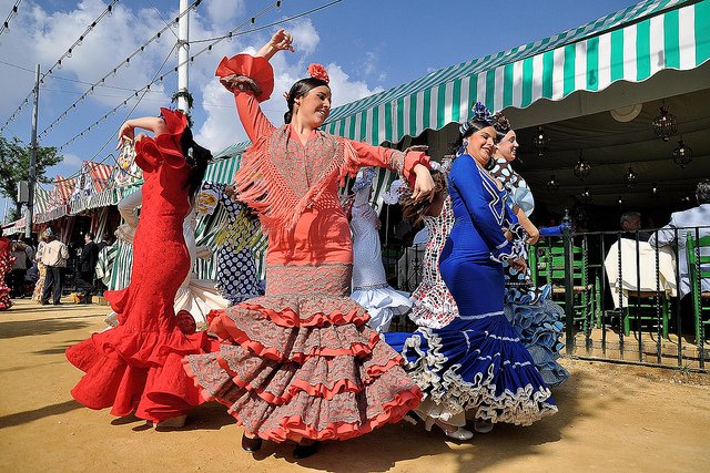 Vrouwen gekleed in de typische  Flamenca jurken, dansen de Sevillanas