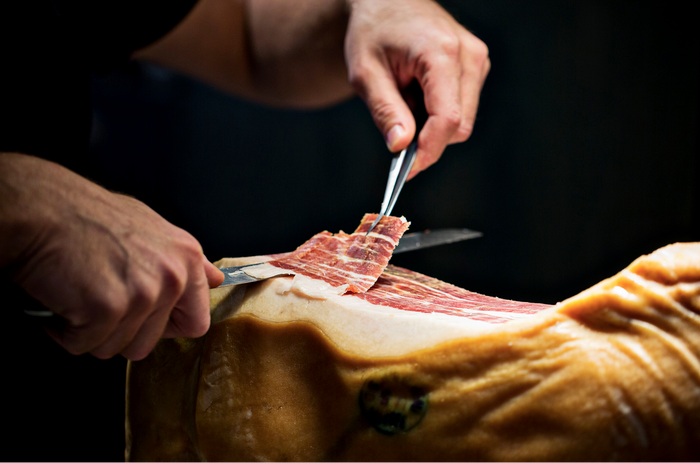 Hand-carving a leg of cured ham